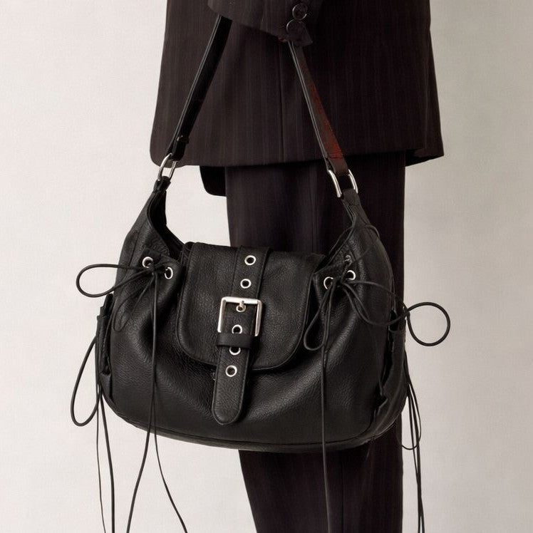 Black pebbled leather-look saddle shoulder bag with lace-up side panels, eyelet detail, and silver buckle flap, detail view 2