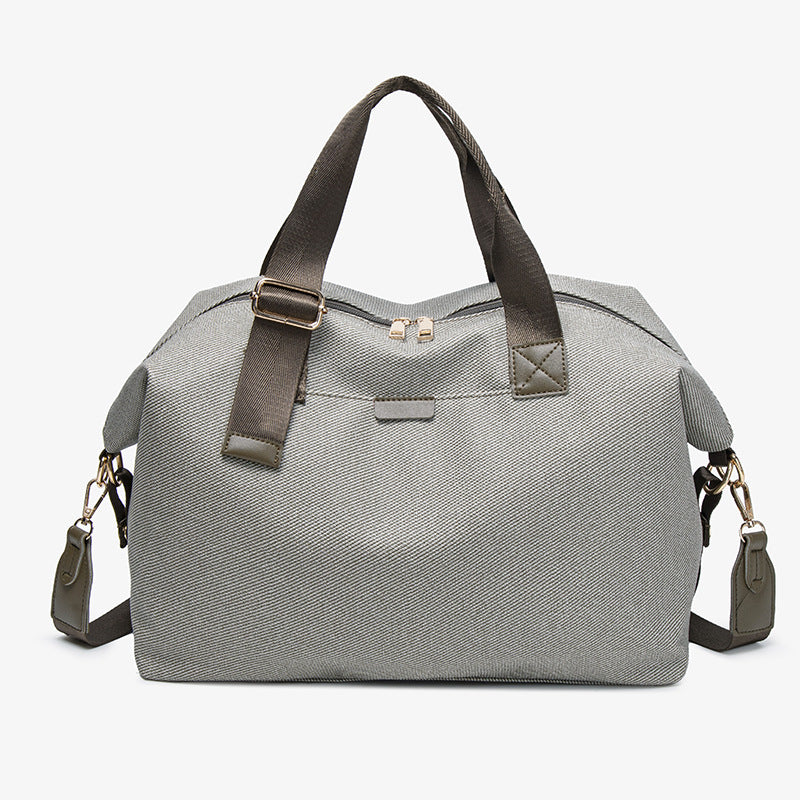 Structured woven duffel bag with dual tan webbing handles, detachable shoulder strap, top zip closure, and gold-tone