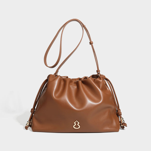 Slouchy ruched drawstring shoulder bag in smooth leather-look finish with gold-tone emblem and slim adjustable strap, detail