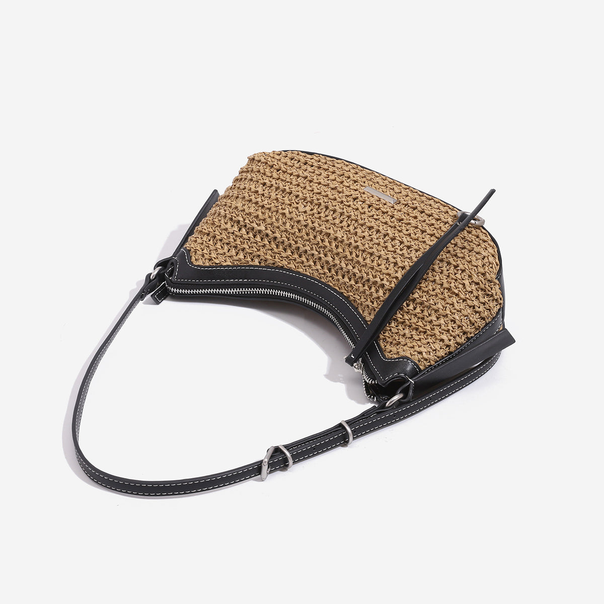Tan woven straw half-moon shoulder bag with black leather-look trim, zip closure, tassel pull, and adjustable crossbody