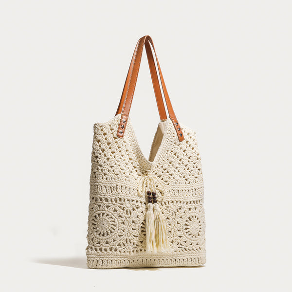 Cream openwork crochet tote bag with tan leather-look double shoulder straps and tassel drawstring tie, detail view 2