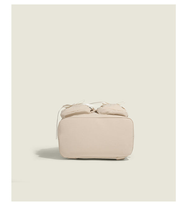 Soft matte nylon drawstring backpack with ruched bow-detail front zip pockets, top carry handle, and silver-tone hardware