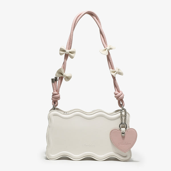 Small structured scalloped-edge shoulder bag with bow-tied pink cord strap and silver heart charm pendant, detail view 6