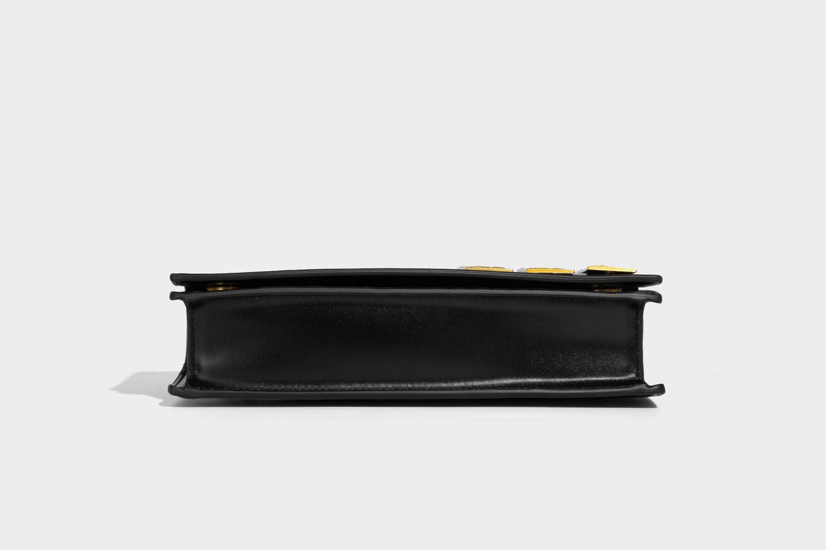 Structured rectangular crossbody bag with glossy finish, three vertical gold-tone embossed plaques, and gold chain strap