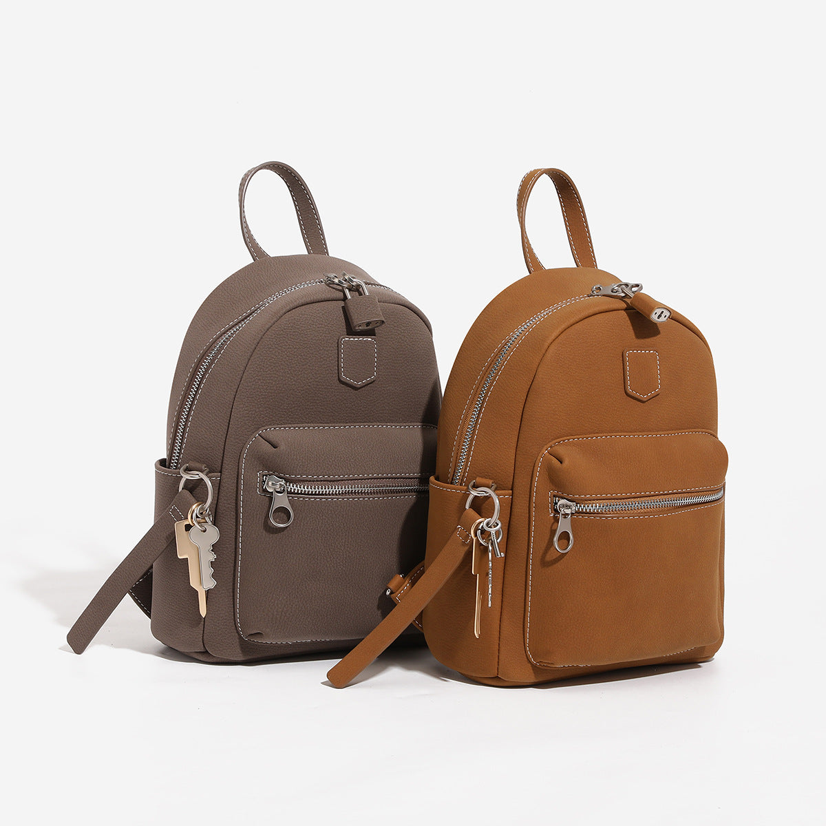 Small rounded mini backpack handbag in pebbled leather-look finish with front zip pocket, silver-tone hardware, and, detail
