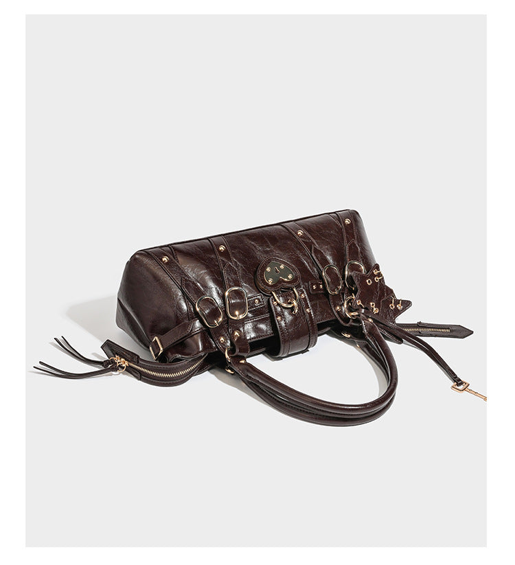 Glossy dark brown structured Boston satchel with heart-shaped lock charm, star pendant, rivet studs, multi-strap front panel