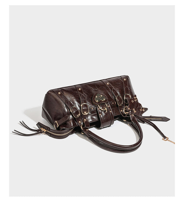 Glossy dark brown structured Boston satchel with heart-shaped lock charm, star pendant, rivet studs, multi-strap front panel