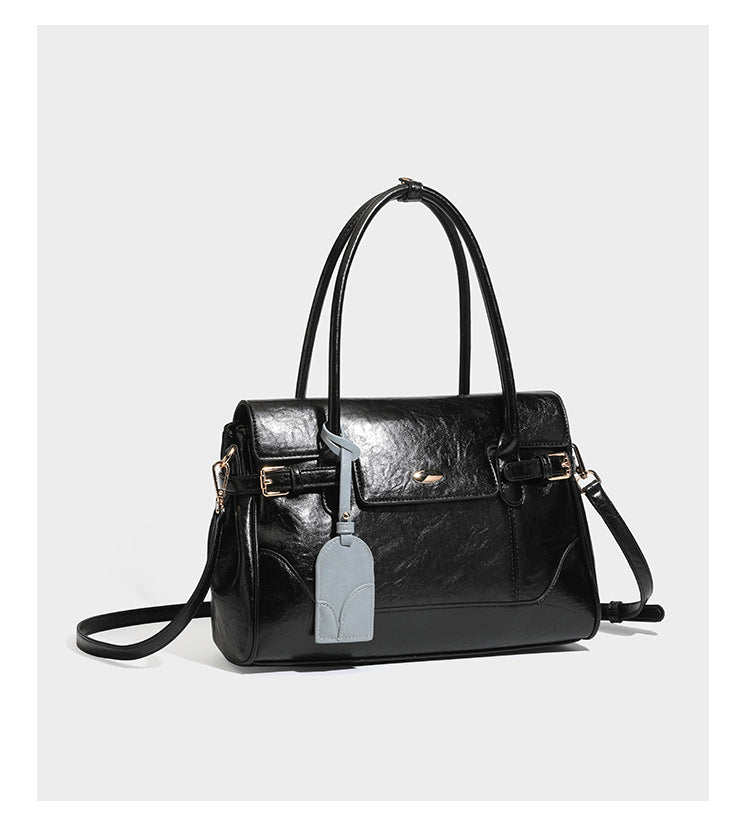 Structured glossy leather-look satchel bag with flap closure, gold-tone buckle accents, double top handles, detachable