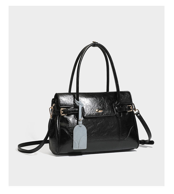 Structured glossy leather-look satchel bag with flap closure, gold-tone buckle accents, double top handles, detachable