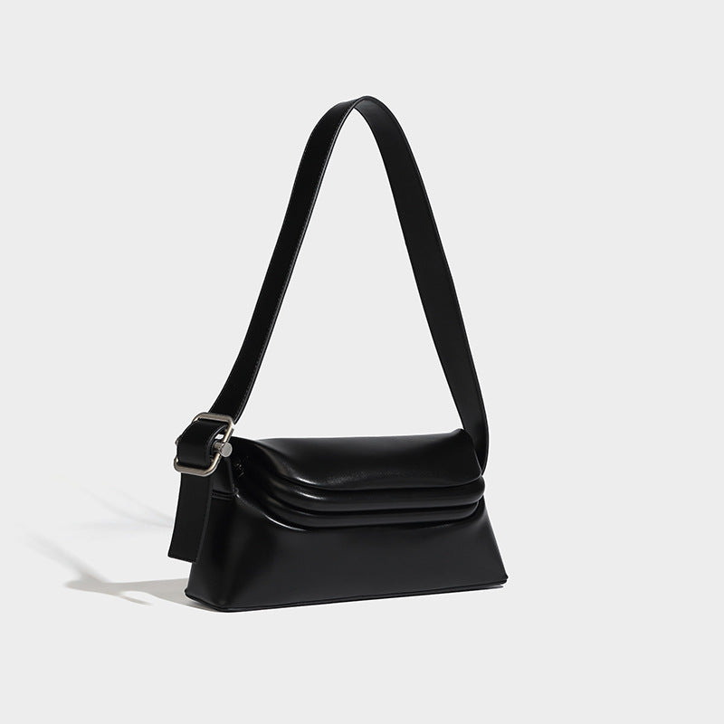 Compact structured baguette shoulder bag with smooth leather-look finish, zip top, and adjustable silver-buckle strap, detail