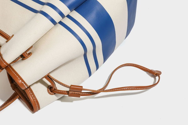Large cream and navy striped canvas bucket tote bag with tan leather-look trim, drawstring closure, and double shoulder