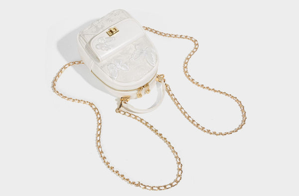 Structured mini backpack handbag with butterfly embroidery, gold-tone chain strap, and turn-lock front flap pocket, detail