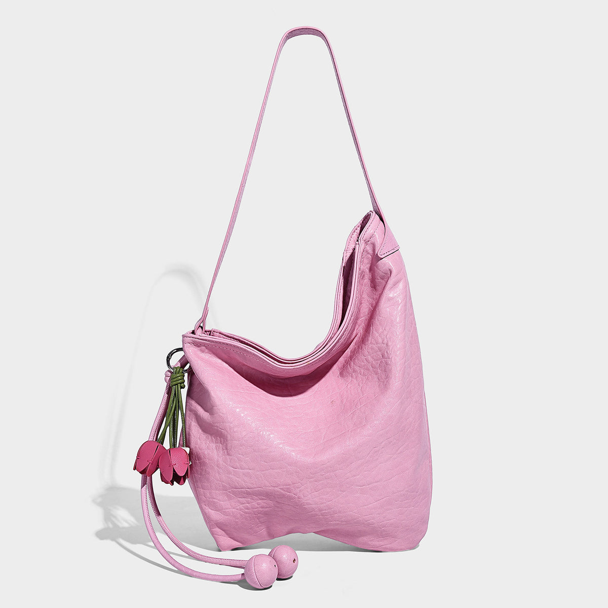 Slouchy hobo shoulder bag in pale yellow with slim strap, drawstring bead closure, and pink tulip floral charm, detail view 3