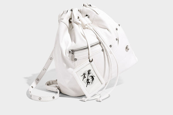 Glossy black convertible bucket backpack with silver grommet-studded straps, drawstring cinch closure, and front zip pocket