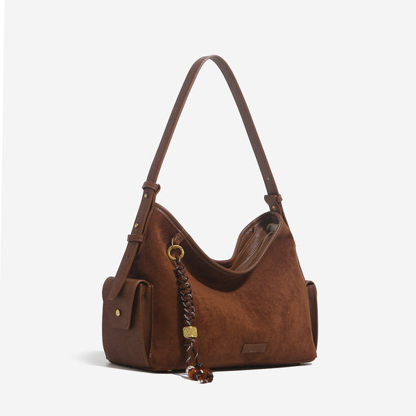 Caramel brown slouchy hobo shoulder bag with matte suede-like finish, braided tassel charm, brass-tone hardware, and, detail