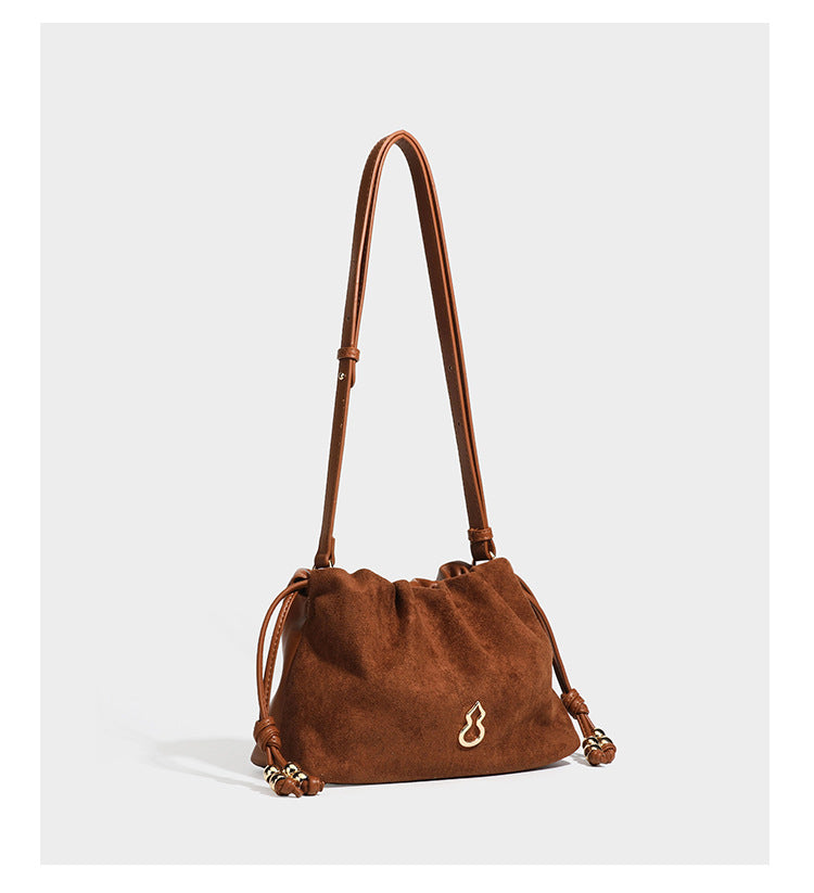 Suede-look drawstring shoulder bag in brown with smooth trim, knotted bead drawstring closure, slim adjustable strap, and