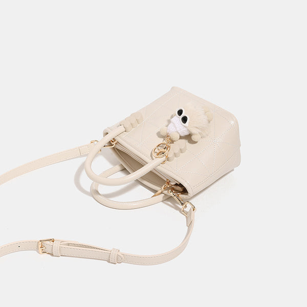 Quilted leather-look mini bucket tote bag with heart-shaped side accents, gold-tone hardware, fuzzy character charm, and