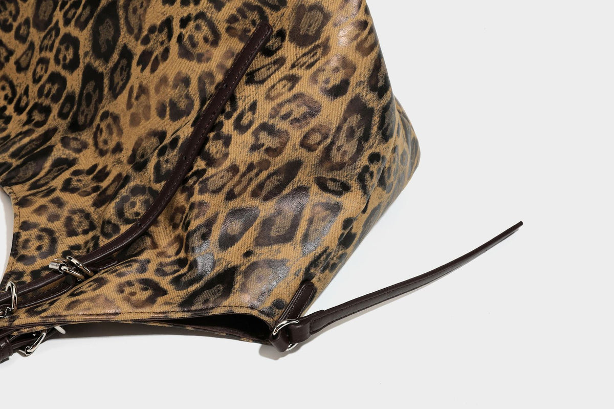 Slouchy leopard-print shoulder tote bag in tan and brown with long double straps, side tie straps, and dangling charm, detail