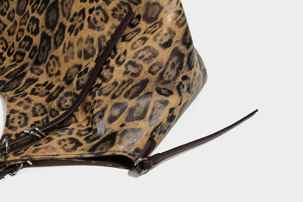 Slouchy leopard-print shoulder tote bag in tan and brown with long double straps, side tie straps, and dangling charm, detail