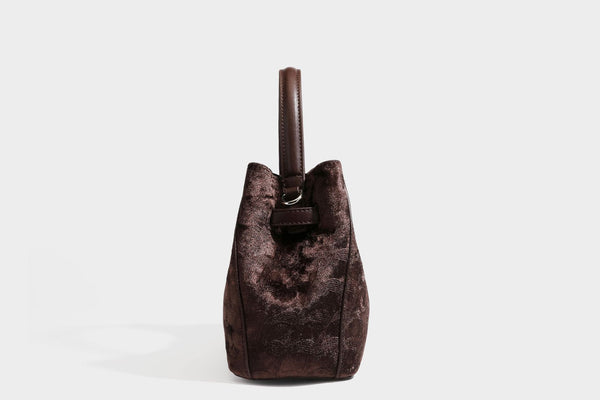 Small structured bucket satchel in embossed velvet-texture fabric with silver turn-lock hardware, rounded top handle, and