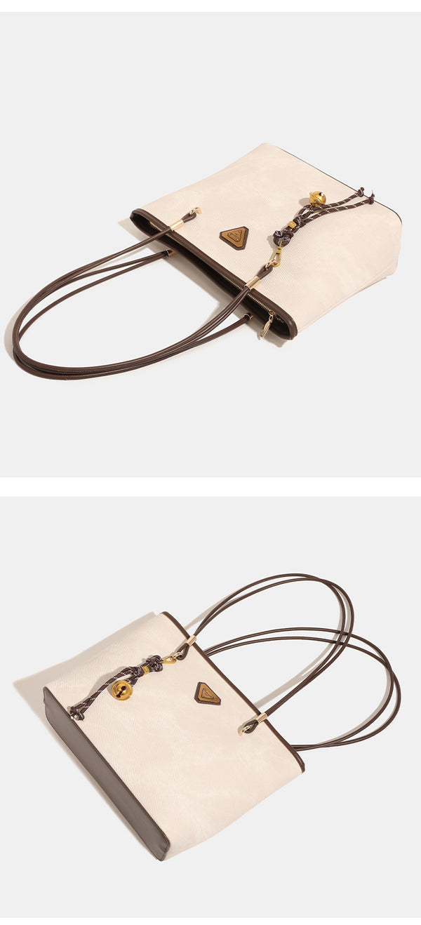 Große, strukturierte Tote-Bag mit offenem Oberteil in Creme, dunkelbrauner Borte in Lederoptik, zwei Schulterriemen und dreieckigem Logo-Badge