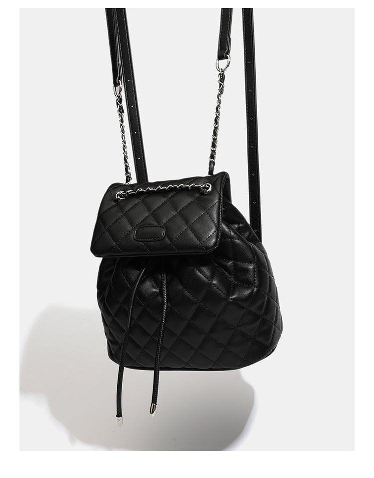 Black diamond-quilted backpack handbag with silver-tone chain flap accent and adjustable shoulder straps, detail view 9