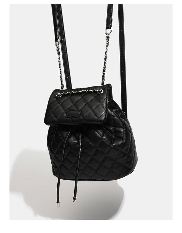 Black diamond-quilted backpack handbag with silver-tone chain flap accent and adjustable shoulder straps, detail view 9