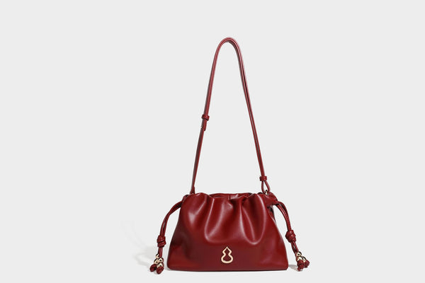Slouchy ruched drawstring shoulder bag in smooth leather-look finish with gold-tone emblem and slim adjustable strap, detail