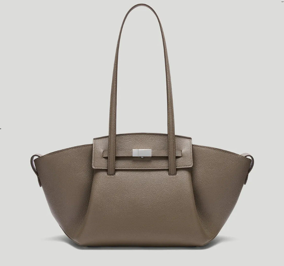 Black pebbled trapezoid tote bag with gold turn-lock hardware and double top handles, detail view 7