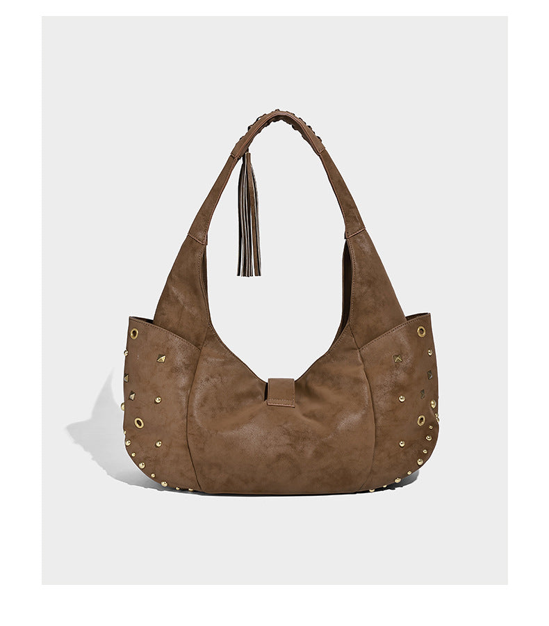 Slouchy crescent hobo bag in matte brown suede-like finish with gold-tone studs, grommets, braided top handle, tassel side
