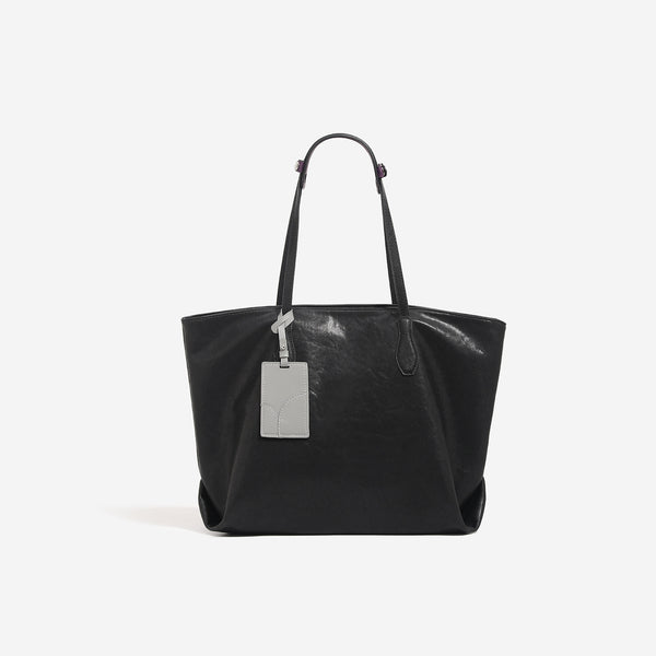 Oversized slouchy leather-look tote bag with long shoulder straps, contrast grey hanging tag, and silver-tone hardware
