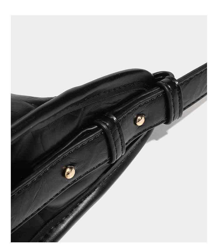 Strukturierte, trapezförmige Schultertasche aus glänzender, geknautscht wirkender Lederoptik mit goldfarbenen Beschlägen auf der Vorderseite und langem, verstellbarem