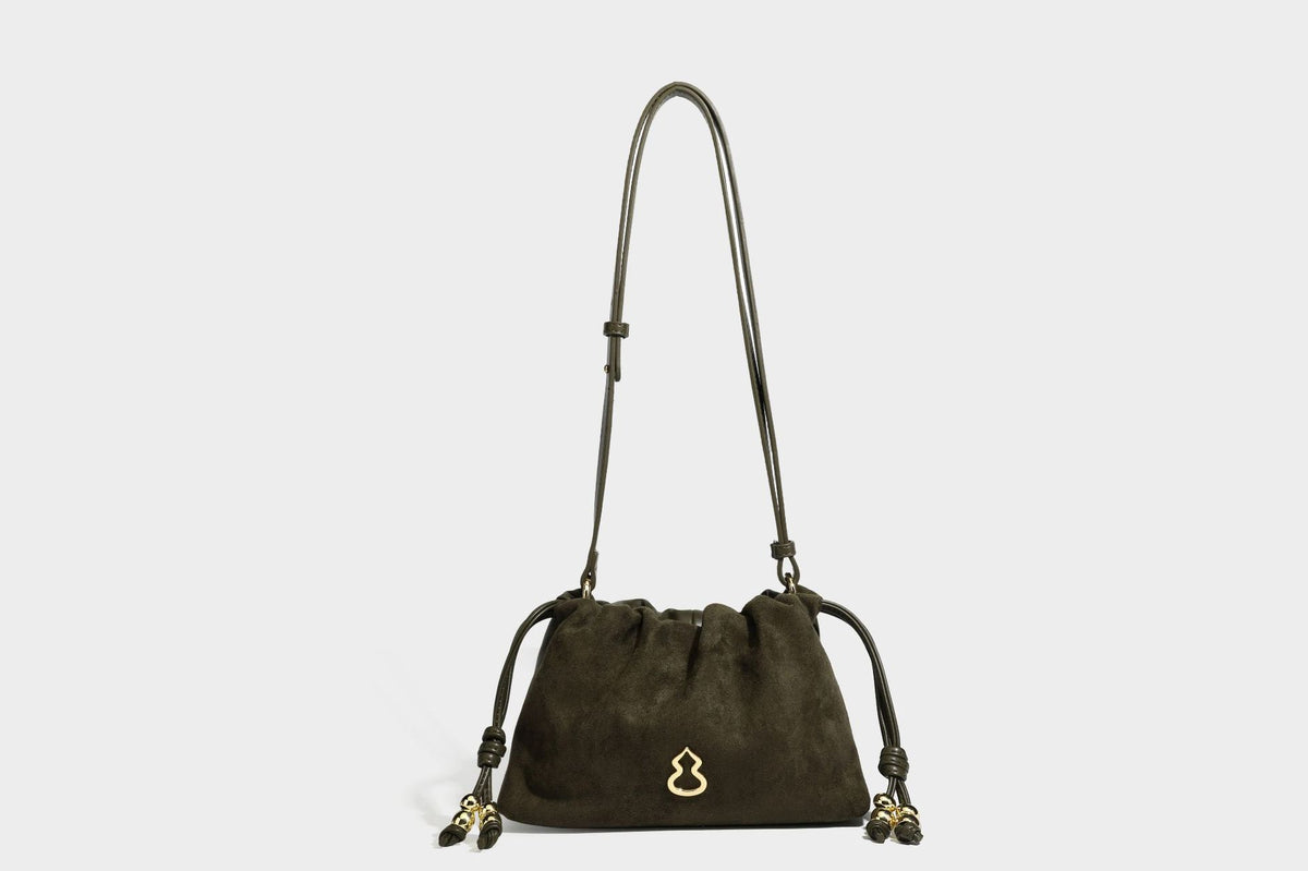 Suede-look drawstring shoulder bag in brown with smooth trim, knotted bead drawstring closure, slim adjustable strap, and