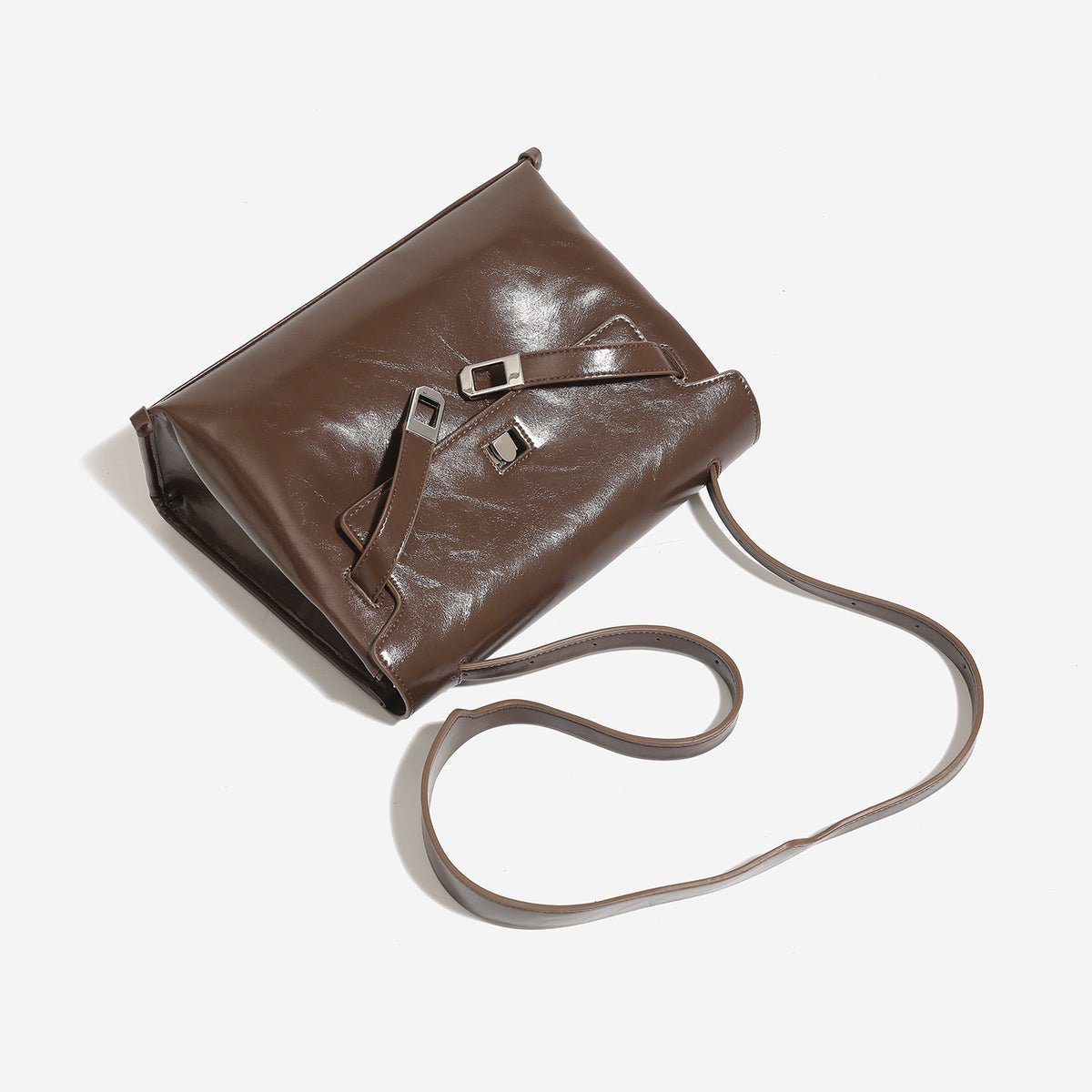 Structured trapezoidal flap satchel bag with silver-tone turn-lock clasp, decorative front strap tabs, gusseted sides, and
