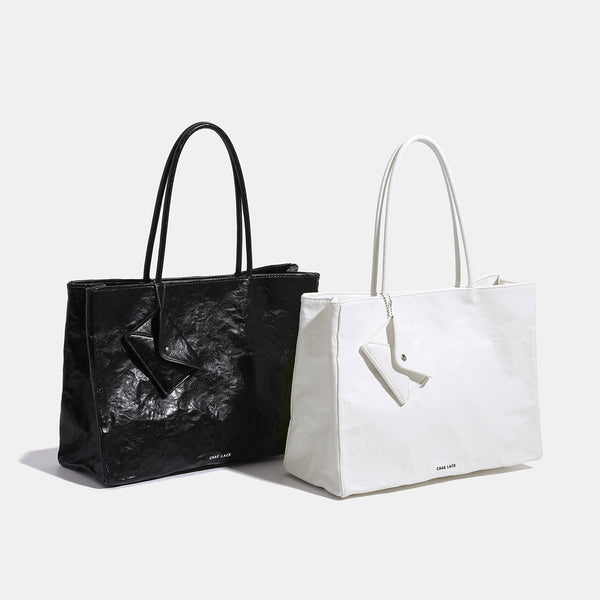 Structured rectangular crinkle leather-look tote bag with long rounded handles, zip top, and envelope-style hanging tag