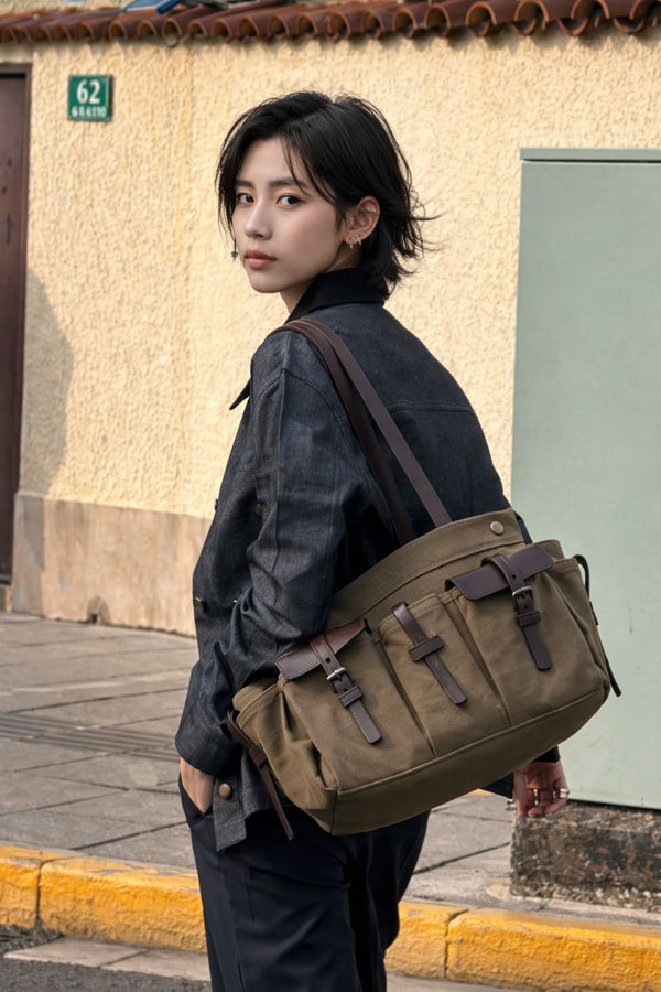 Large olive canvas shoulder tote bag with multiple front buckle-strap pockets and dark brown leather-look trim, detail view
