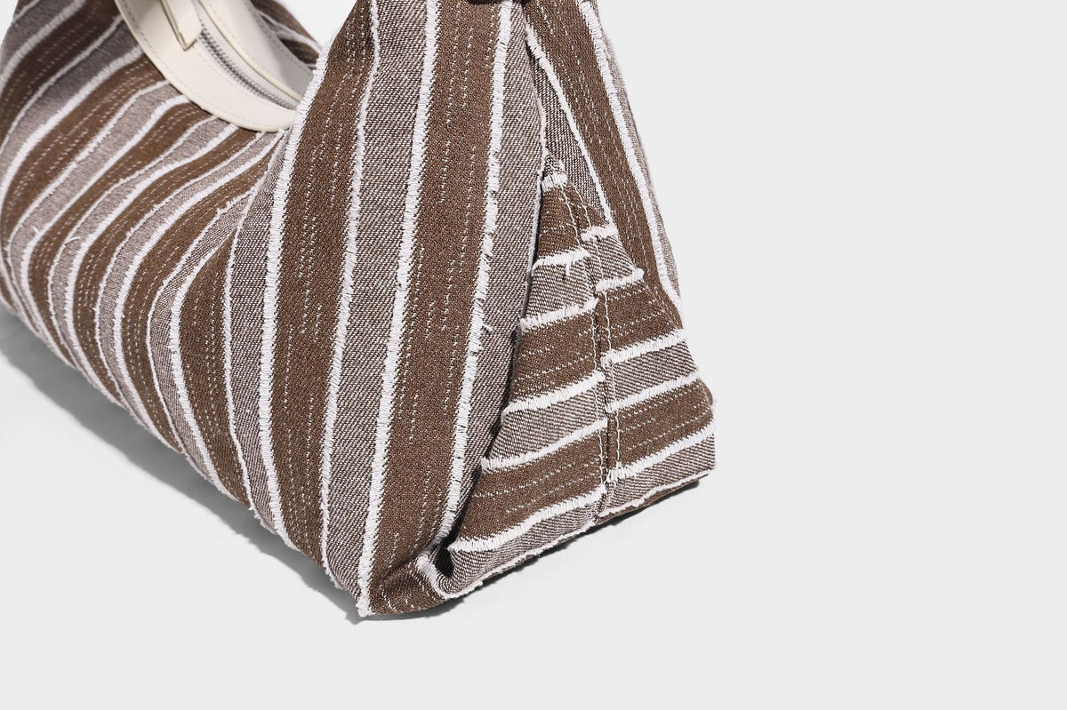 Lässig fallende, gestreifte gewebte Hobo-Bag mit kontrastierendem cremefarbenem Besatz, Reißverschluss oben und verstellbarem Riemen mit Schnalle in Silberoptik, Detailansicht