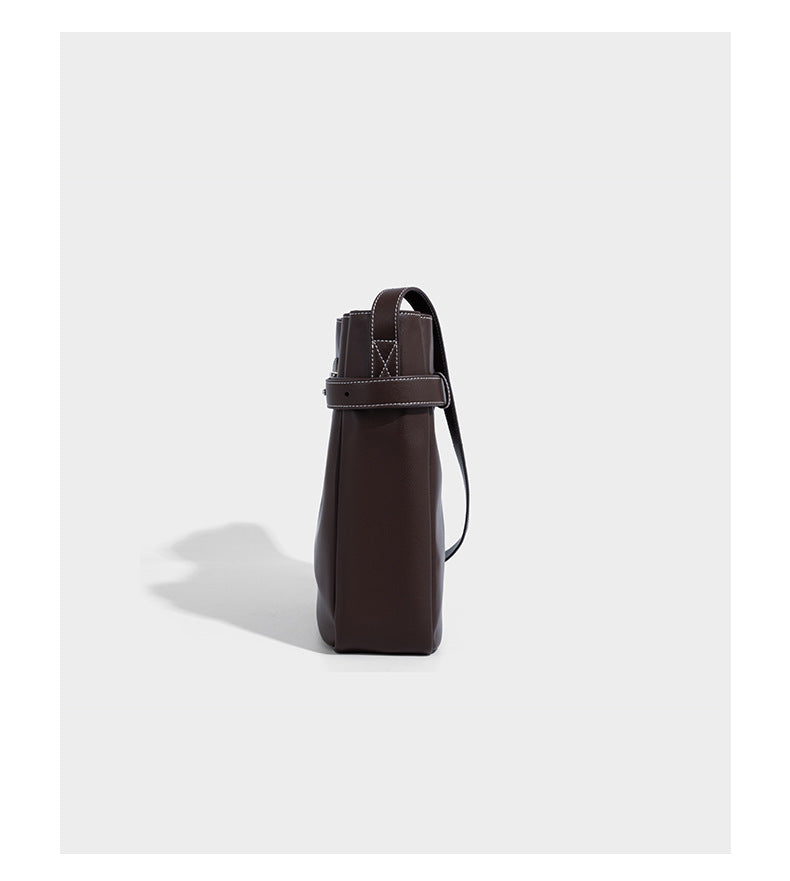 Structured dark brown leather-look bucket bag with white contrast stitching, front wraparound belt buckle strap, and long