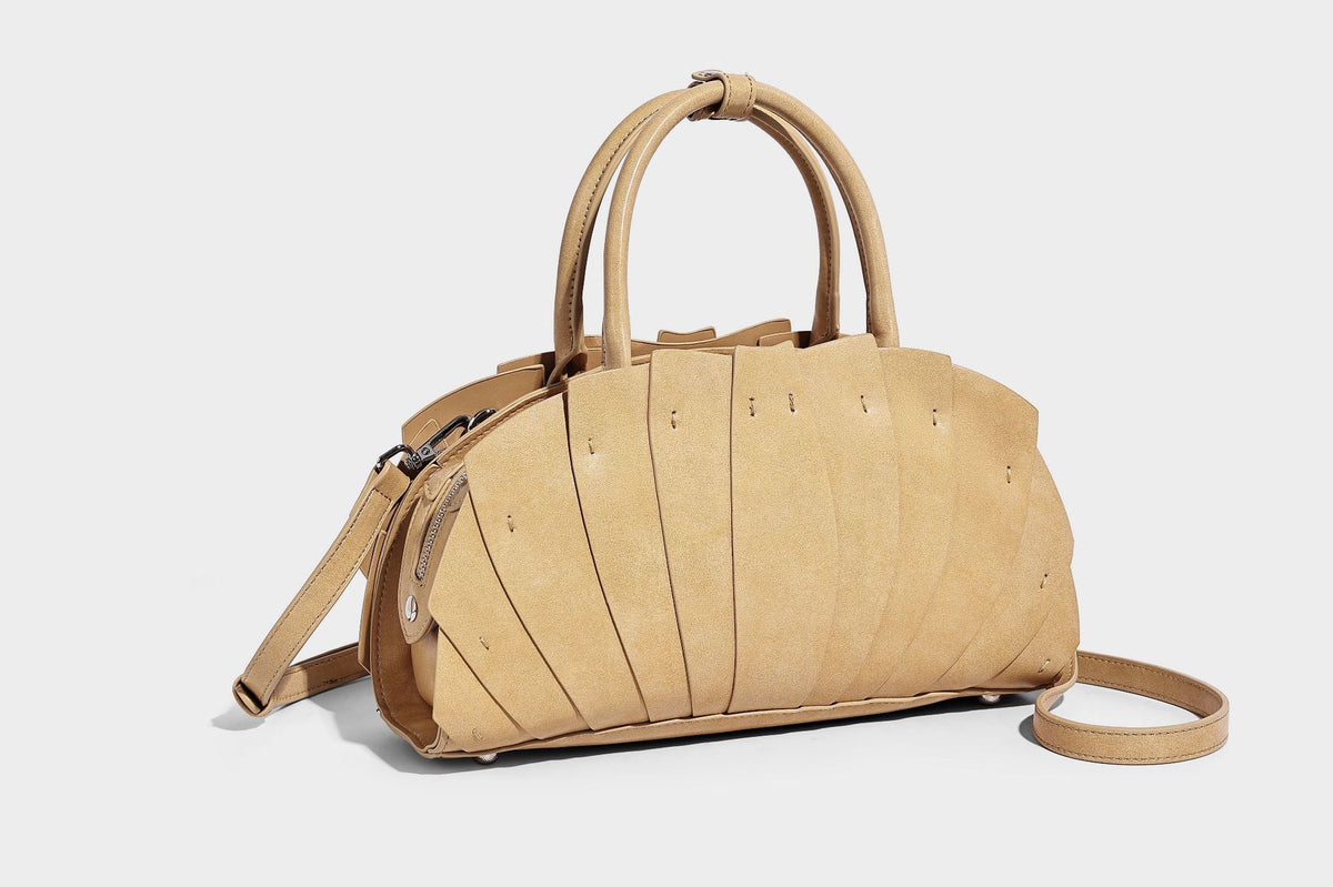 Structured dome satchel with fan-pleated leather-look exterior, dual top handles, and detachable shoulder strap, detail view