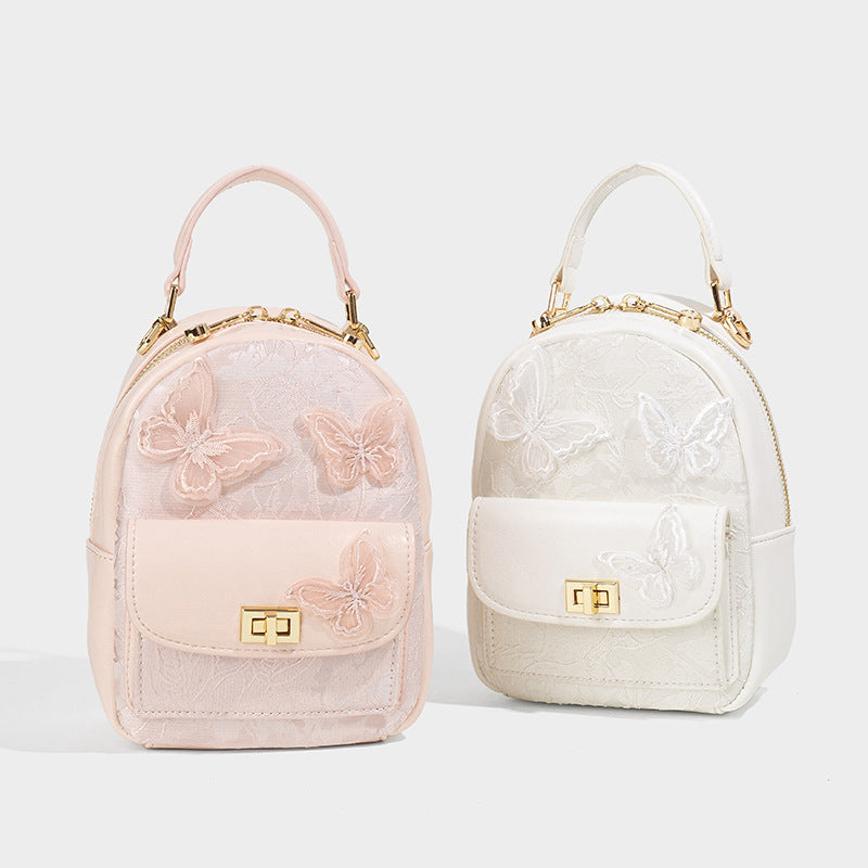 Structured mini backpack handbag with butterfly embroidery, gold-tone chain strap, and turn-lock front flap pocket, detail