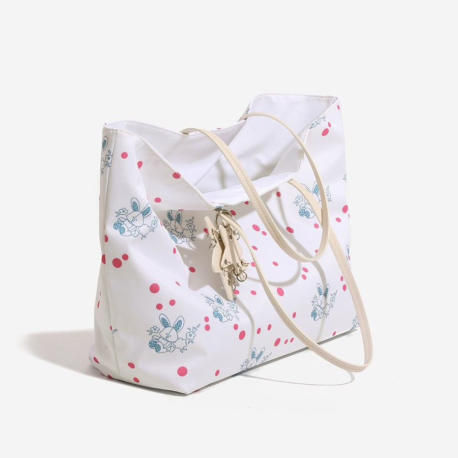 Large reversible floral print tote bag with slim shoulder straps, star charm hardware, and matching zip pouch, detail view 3