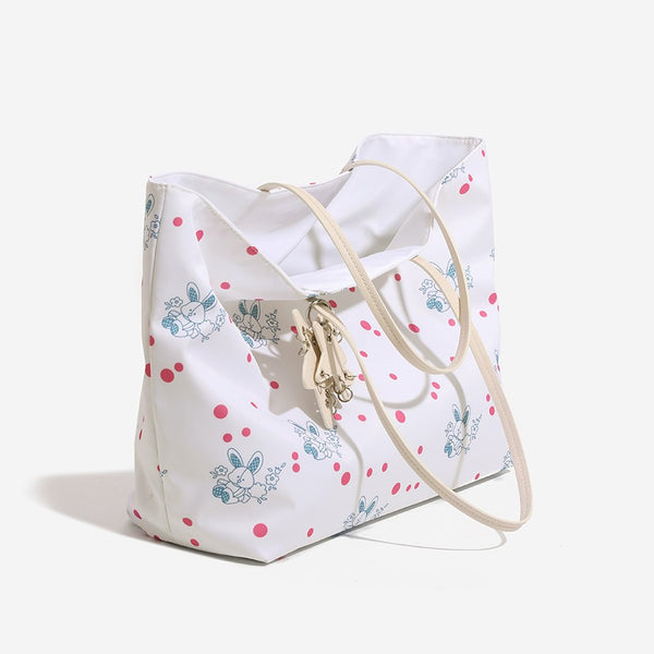 Large reversible floral print tote bag with slim shoulder straps, star charm hardware, and matching zip pouch, detail view 3