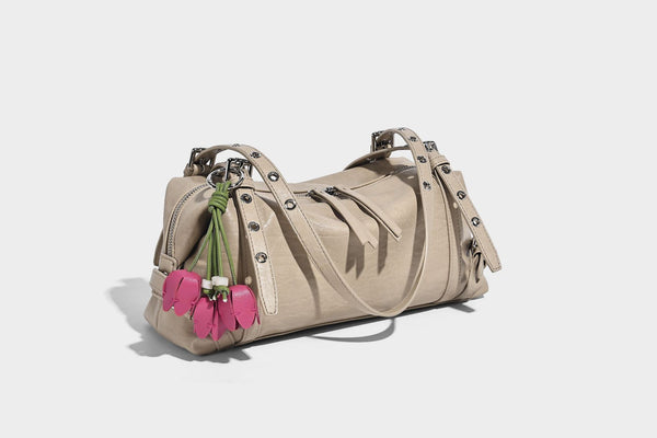 Pale yellow leather-look barrel bag with silver grommet-studded shoulder straps, top zip closure, and pink tulip floral