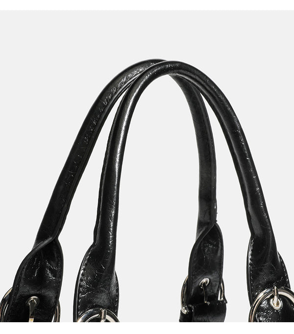 Compact black glossy leather-look satchel bag with silver-tone rivets, buckle hardware, and dual padded top handles, detail