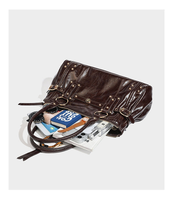 Dark brown glossy leather-look structured satchel tote with gold-tone studs, buckle straps, dual top handles, and detachable