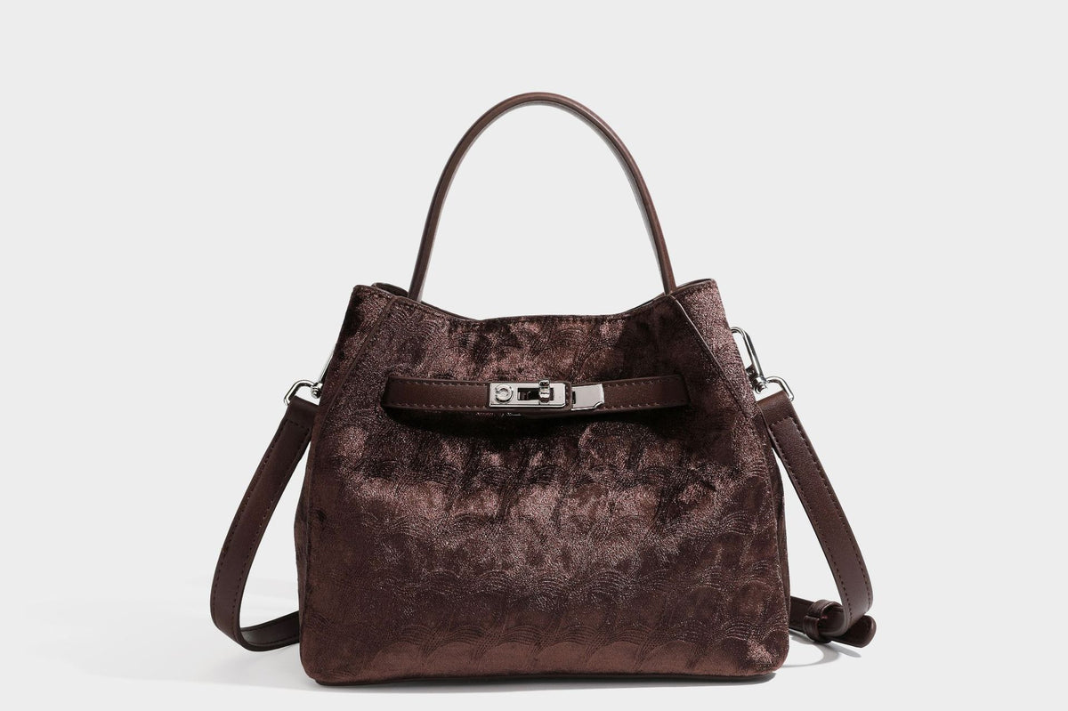 Small structured bucket satchel in embossed velvet-texture fabric with silver turn-lock hardware, rounded top handle, and