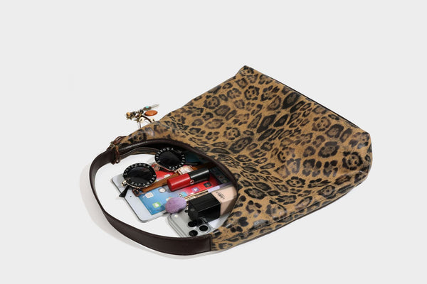 Lässige Hobo-Shopper-Tasche mit Leopardenmuster in Tan und Braun, dunkelbraunem Riemen in Lederoptik und herabhängendem Perlenanhänger an den Beschlägen