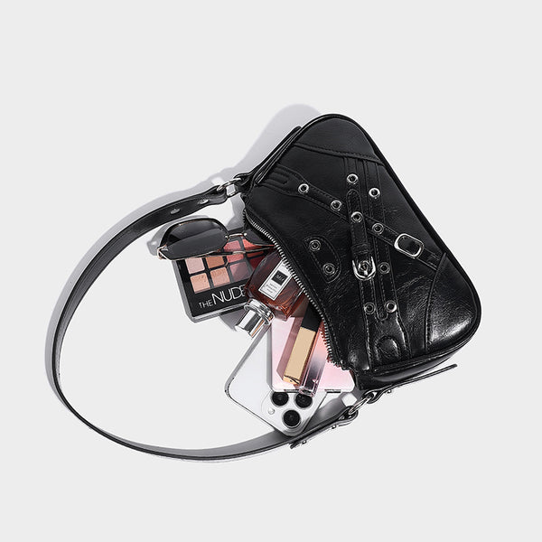 Compact moto-inspired shoulder bag with crisscross grommet strap detail, glossy textured finish, and adjustable crossbody