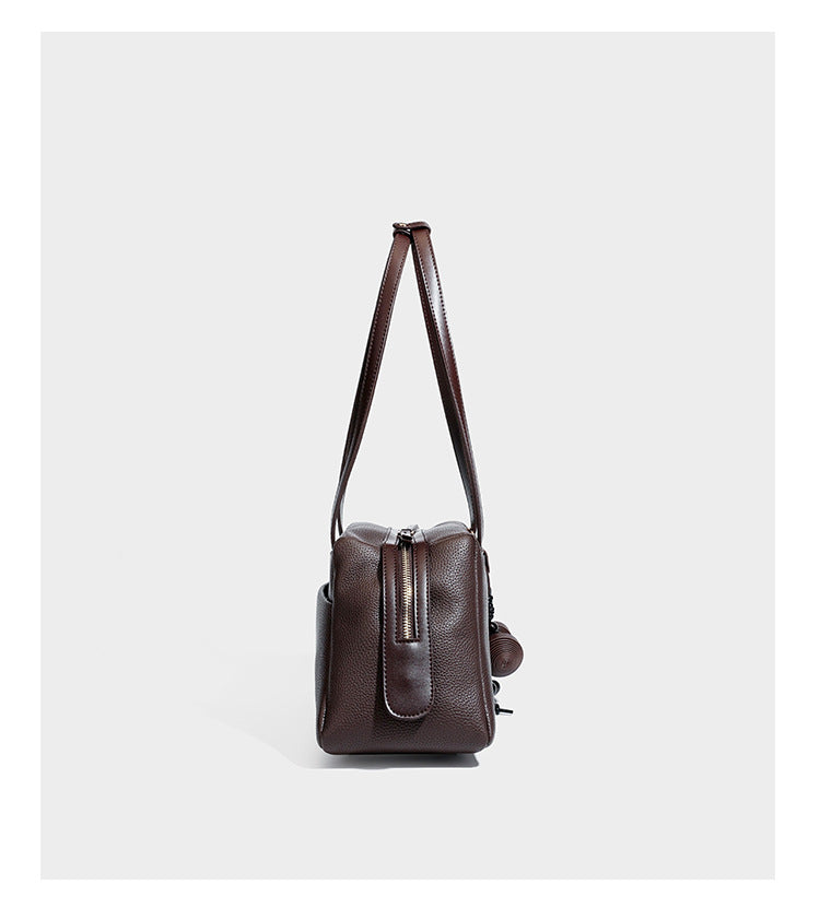 Structured trapezoid shoulder bag in dark brown pebbled leather-look finish with slim double straps, top zip closure, side