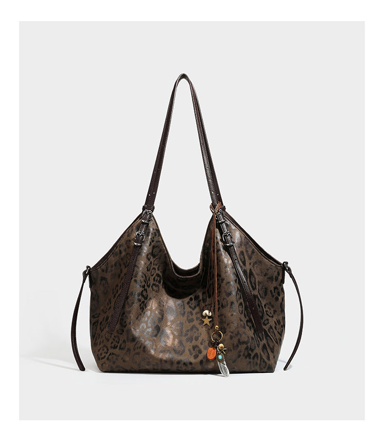 Slouchy leopard-print shoulder tote bag in tan and brown with long double straps, side tie straps, and dangling charm, detail